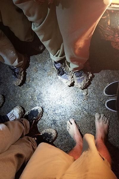 top view of Brenda and boys' muddy feet as they stand in a circle